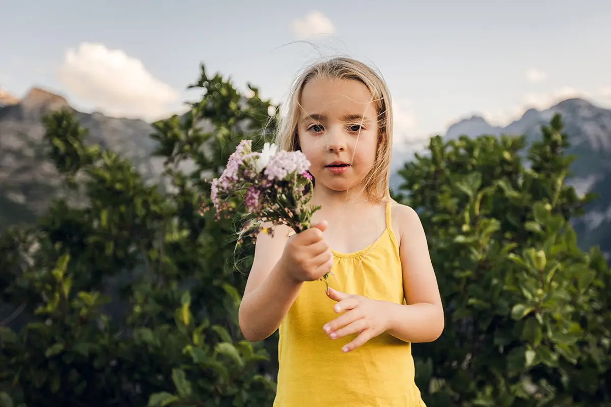 enfant avec un bouquet de fleur en montagne